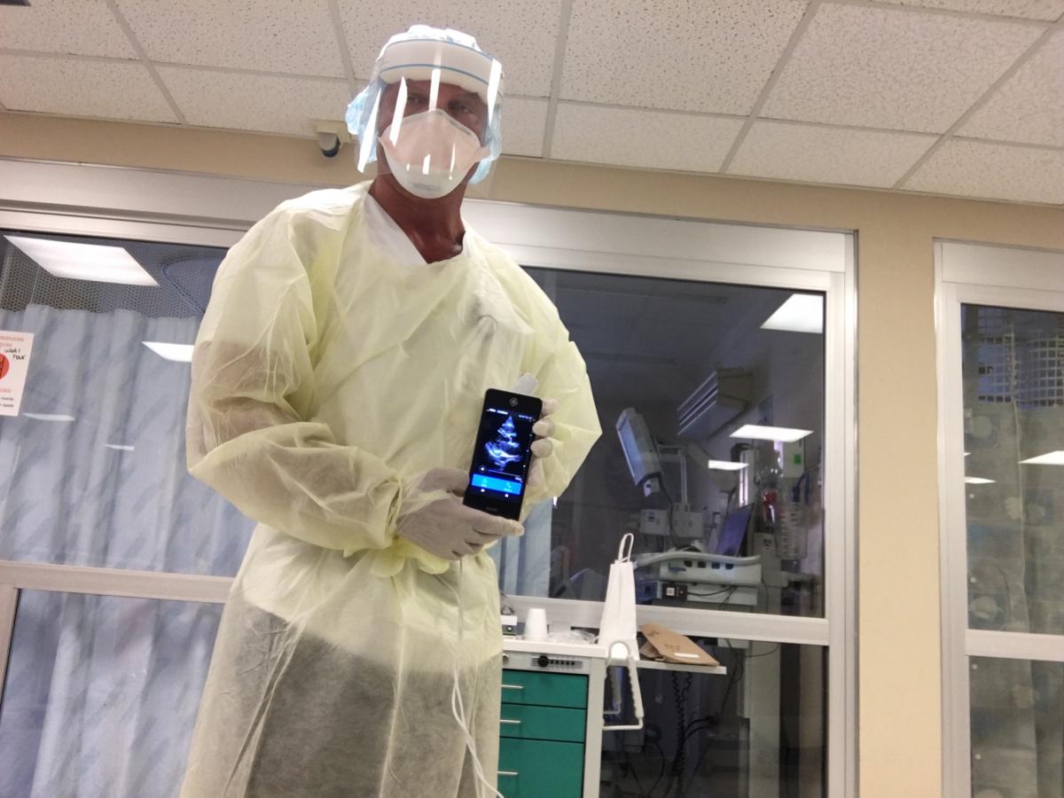 Naples Community Hospital Director of Cardiac Imaging Bill Shirkey showing a point-of-care echocardiogram of a COVID-19 patient he imaged with a GE Healthcare Vscan device bedside in an isolation room. Use of a small handheld device greatly speeds disinfection after the exam and does not require moving a larger cart-based ultrasound system into a room, which may require moving furniture and add exposure time in the room.