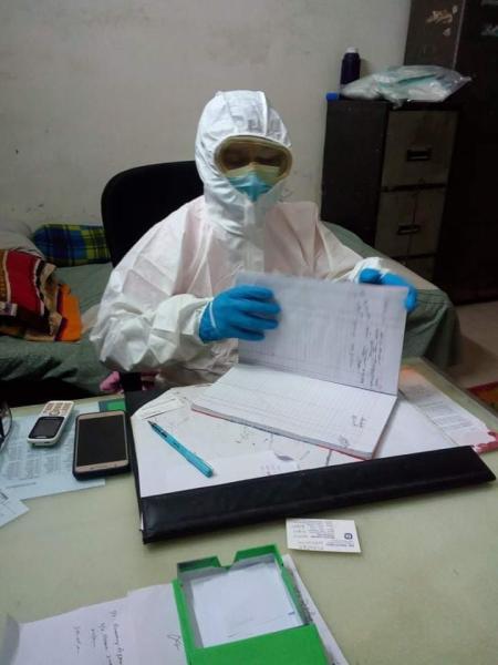 A doctor in their office in Bangladesh wearing full personal protective equipment (PPE) in between seeing patients. The cot behind the doctor is because of the long shifts they are required to do because of the shortage of doctors. Photo by Aster Azalea.