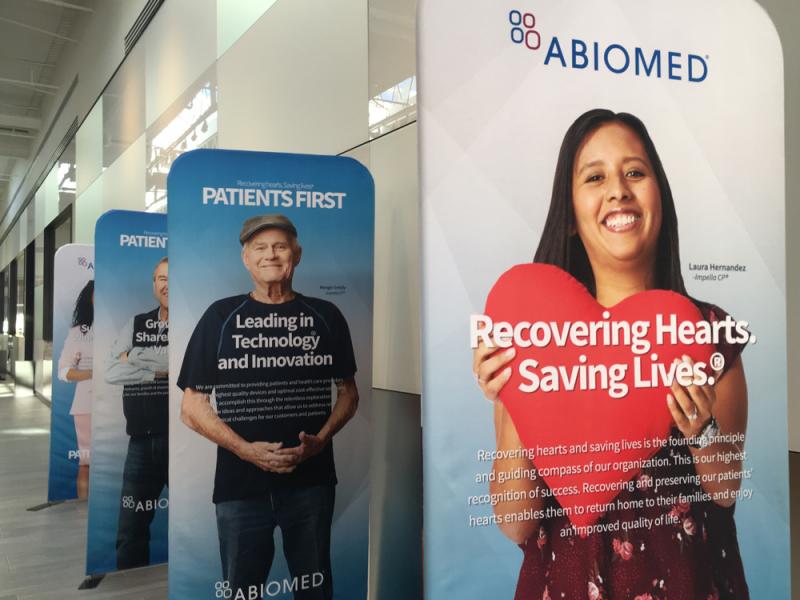 There are several reminders around the Abiomed headquarters office that the products employees there make are designed to help save lives. These are among many posters of actual patients who received Impella devices, which helped their survival.