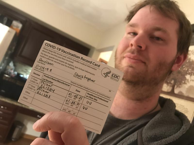 Iowa nursing home worker Christopher Davison shows off his COVID vaccine card. Since he works at a nursing home facility, he was among the first in line for the vaccine in December 2020 and January 2021. Photo by Dave Fornell