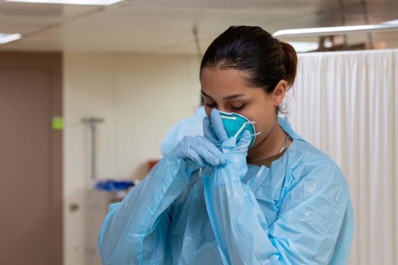 Hospitalman Pearl Alvarado, a native of San Antonio, dons a face mask aboard the hospital ship USNS Mercy (T-AH 19) before working with a patient. Mercy deployed in support of the nation's COVID-19 response efforts, and will serve as a referral hospital for non-COVID-19 patients currently admitted to shore-based hospitals. This allows shore base hospitals to focus their efforts on COVID-19 cases. U.S. Navy photo by Mass Communication Specialist 2nd Class Abigayle Lutz.