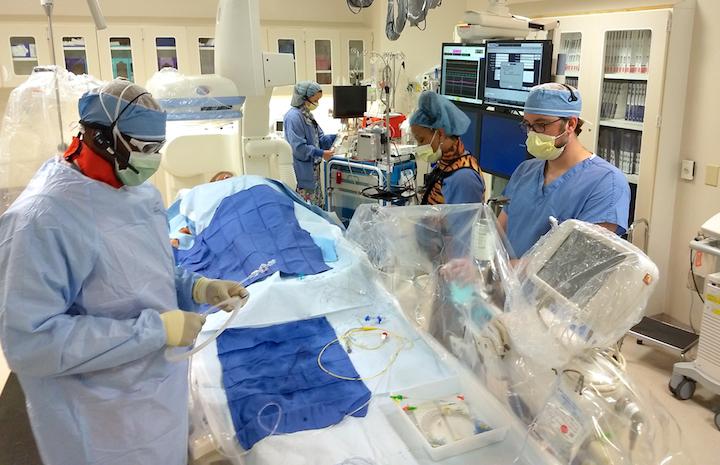 Cath lab staff working as a team to prepare for a procedure at Presbyterian Medical Center Cardiac Cath Lab, Charlotte N.C. Pictured are Barry Horsey RCIS, Emily Luna RN, RCIS, Adam Martin RCIS, Caleadia Jessup RN.