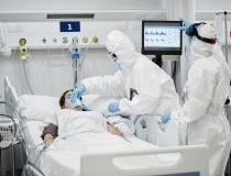 A COVID patient on a ventilator in an ICU. The clinicians are wearing larger photos of themselves to help build better relations with their patients and make it easier for fellow staff to see identify who they are under the PPE. 